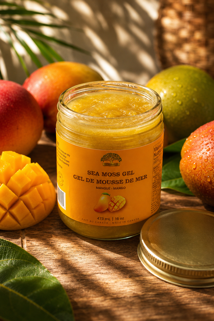 Jar of sea moss gel surrounded by mangoes on a wooden surface with a natural background